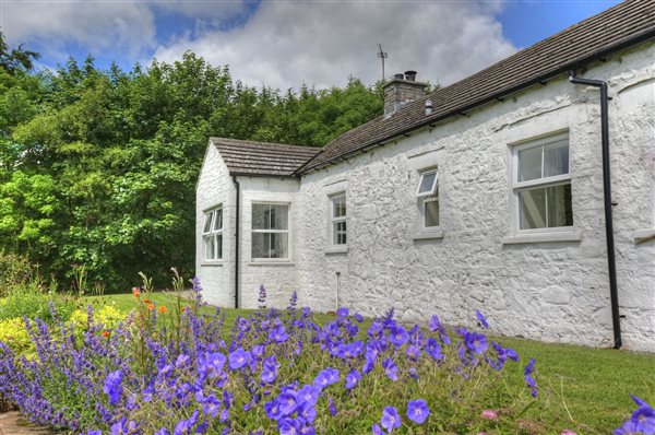 White painted bungalow with flower bed and lawn