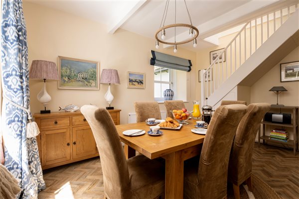 Dining room with table and chairs, two windows and side board with table lamps