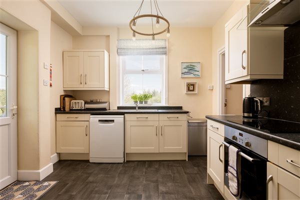 Kitchen with dishwasher, surfaces, cooker and door to patio