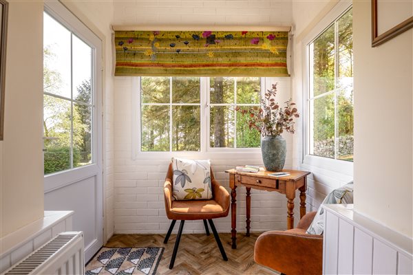 Porch with side table and two chairs is a suntrap with windows and door to garden