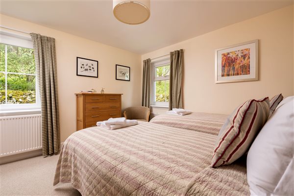 Downstairs bedroom with twin beds, two windows with garden views