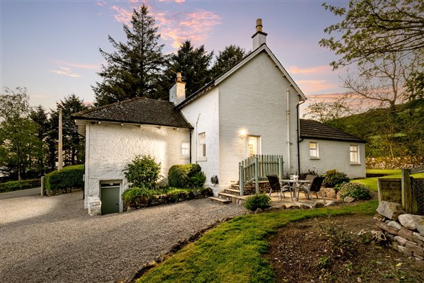 Photo of white painted cottage at dusk