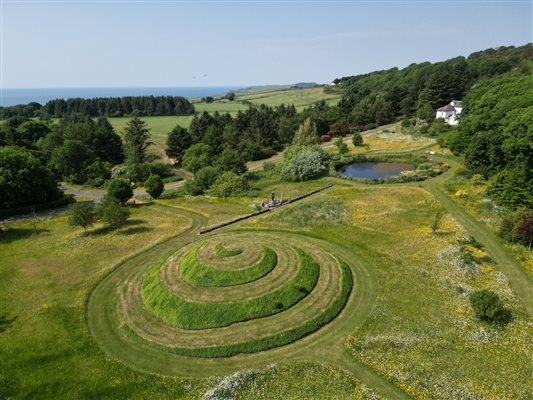 Drone picture of Cutlar's Lodge with wildflower meadow in front and sea in the distance